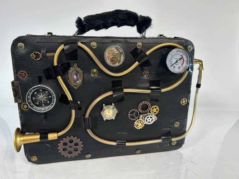 A black Goth style black purse with skulls and other objects on it.