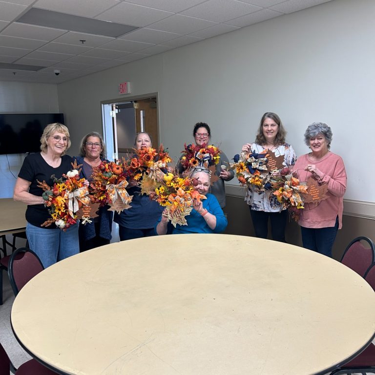 A group of six women holding wreaths the designed during a workshop.