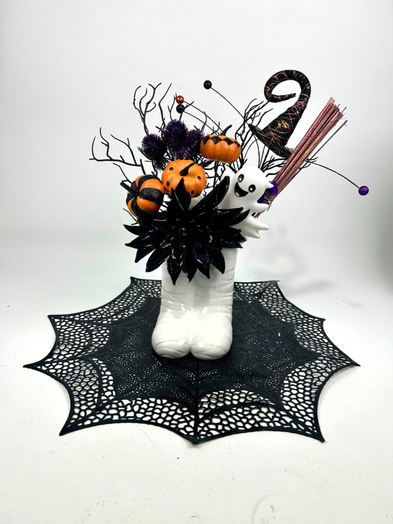 A Halloween themed centerpiece in orange and black on a web shaped black mat.